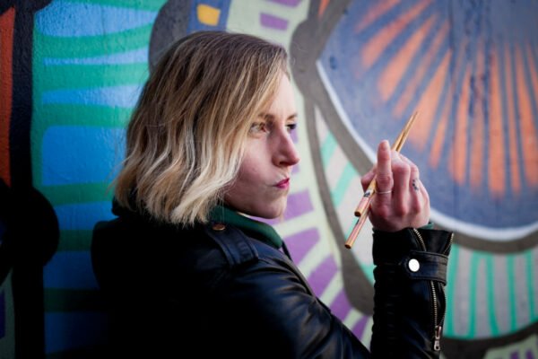 Femme qui tient baguettes pour manger nouilles devant un mur coloré pour illustrer sa reconversion insolite