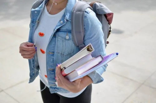 Femme avec livres dans la main qui va reprendre ses études et les financer