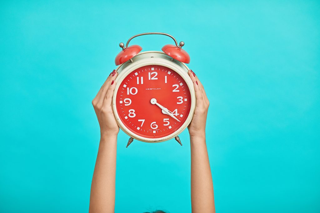 Horloge rouge sur fond bleu qui illustre la procrastination
