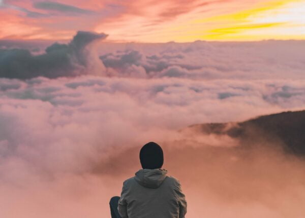 Un homme devant l'horizon assis sur une montagne
